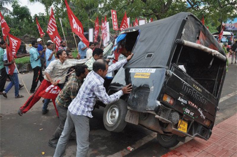 Striking Indian workers pushing over a scab van